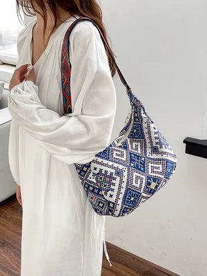 Embroidered geometric hobo bag in blue with a colorful woven strap.