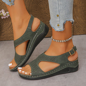 Green cutout wedge sandals with adjustable ankle strap and perforated details.