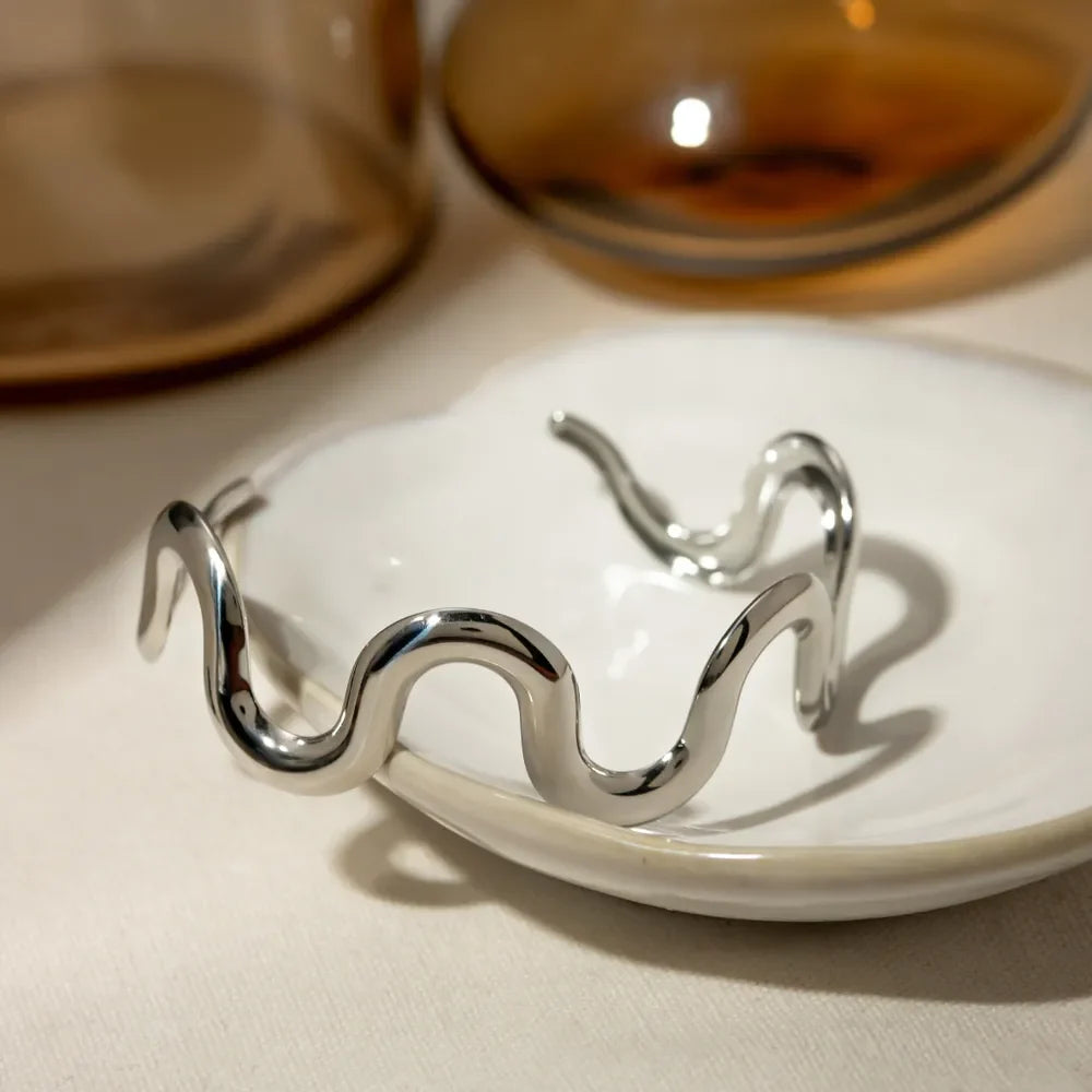Sculptural silver cuff bracelet with a wavy, ripple design.