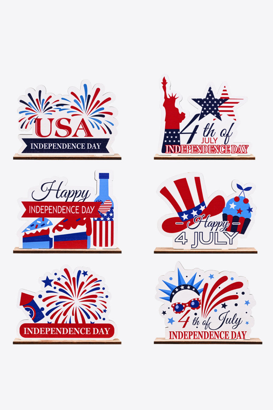Patriotic wooden tabletop decor with USA, Statue of Liberty, cakes, bottle, hat, and fireworks designs.