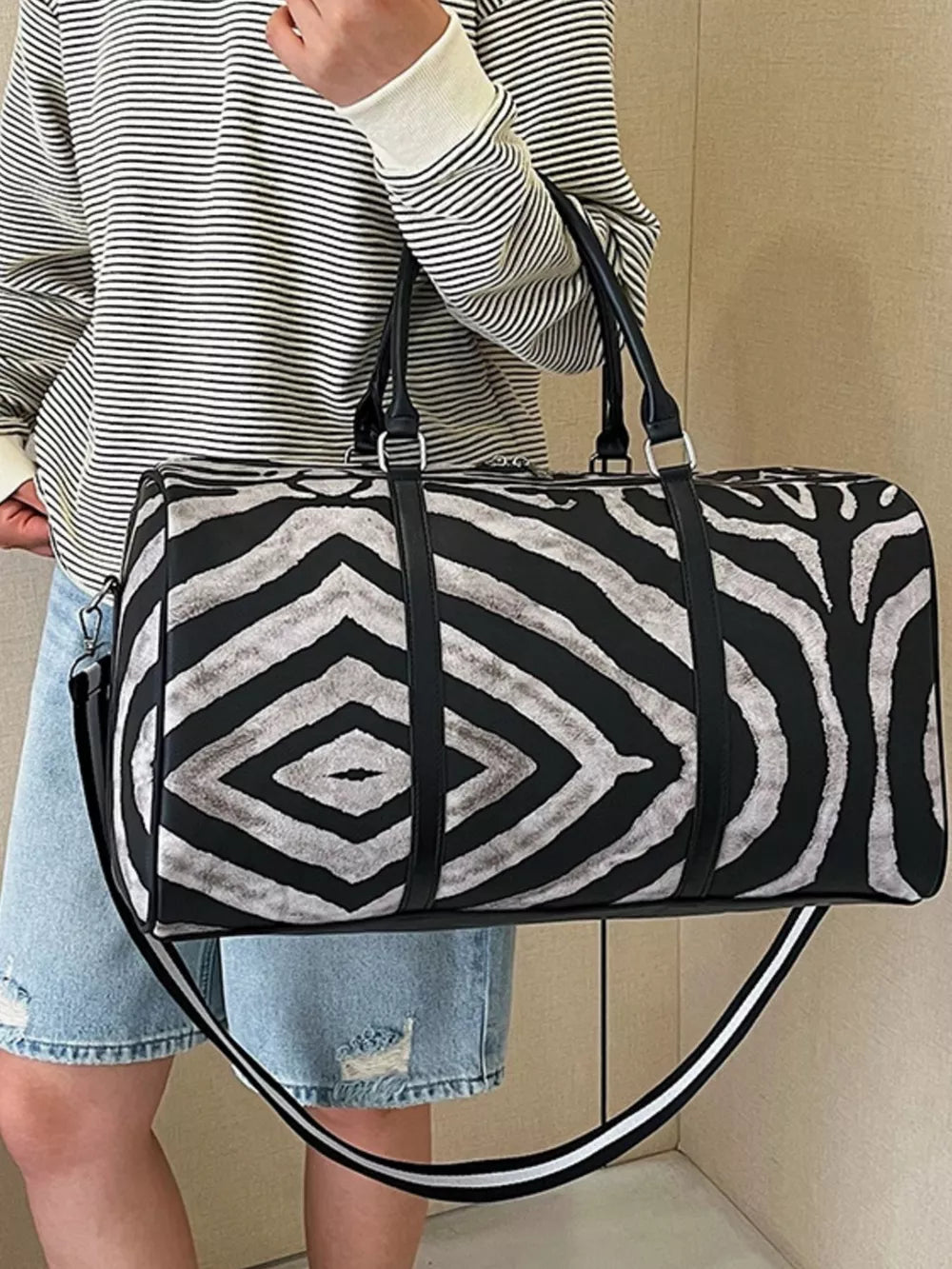 Bold zebra print duffle bag with black carry handles and detachable strap.