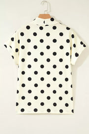 Cream polka dot short sleeve shirt with a mock neck and cuffed sleeves.