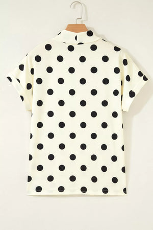 Cream polka dot short sleeve shirt with a mock neck and cuffed sleeves.