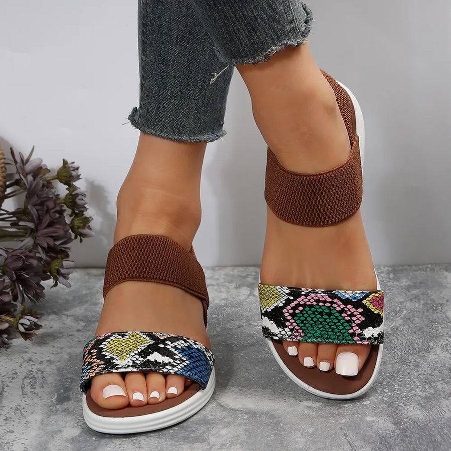 Geometric print elastic strap sandals with brown ankle straps and multicolor snake print toe straps.