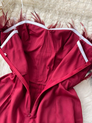 Wine red strapless wide-leg jumpsuit with feather trim detail.