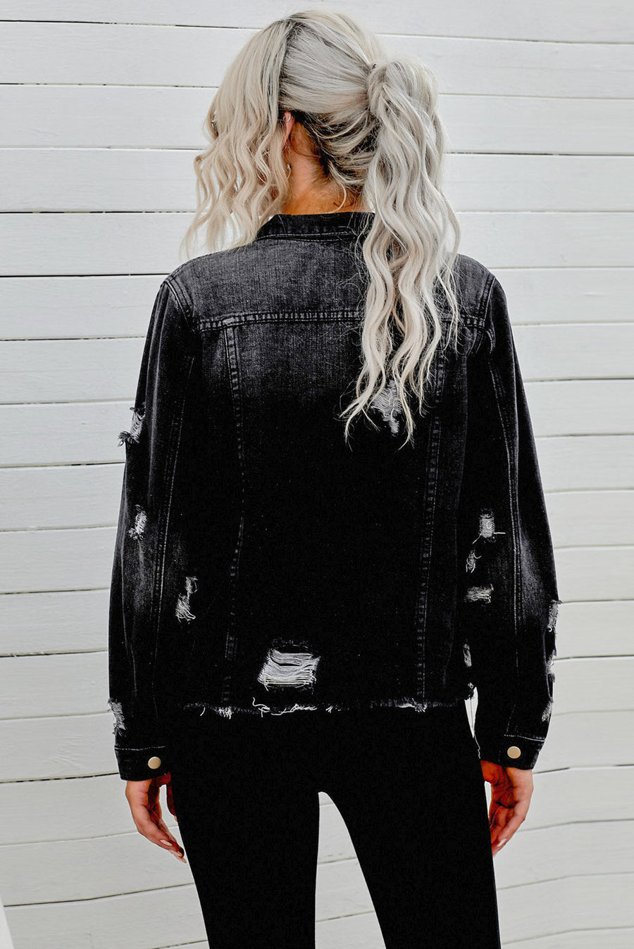 Black distressed denim trucker jacket with frayed edges and ripped details.