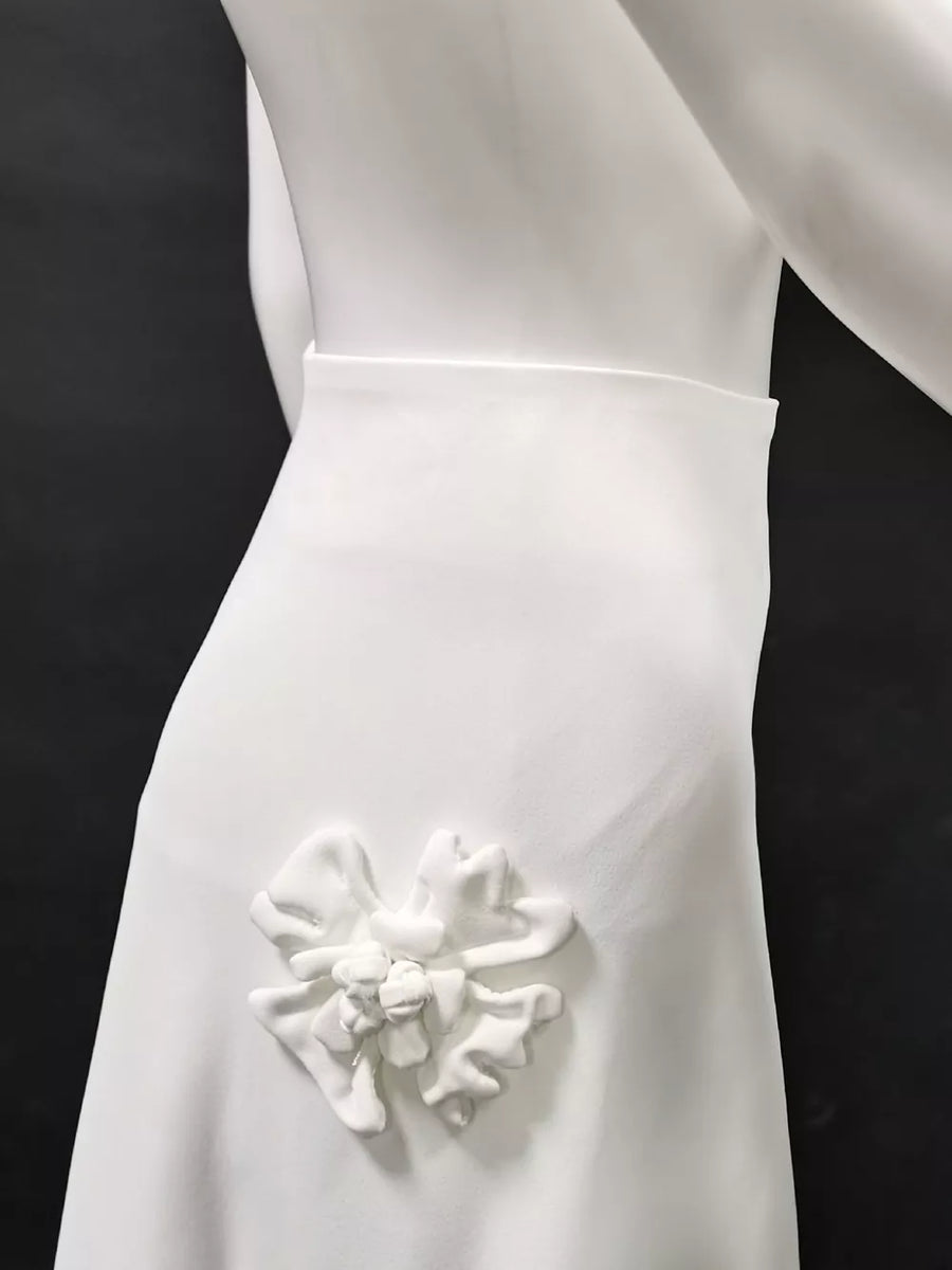 White dress with a 3D floral applique detail on the hip.