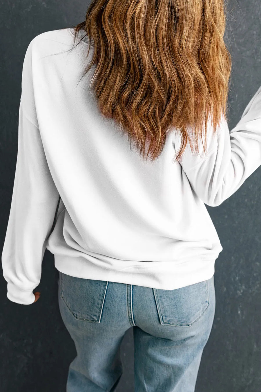 White crewneck sweatshirt with long sleeves, styled with jeans.