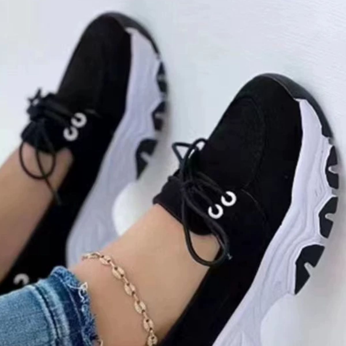 Black lace-up sneakers with white chunky soles and round toes.