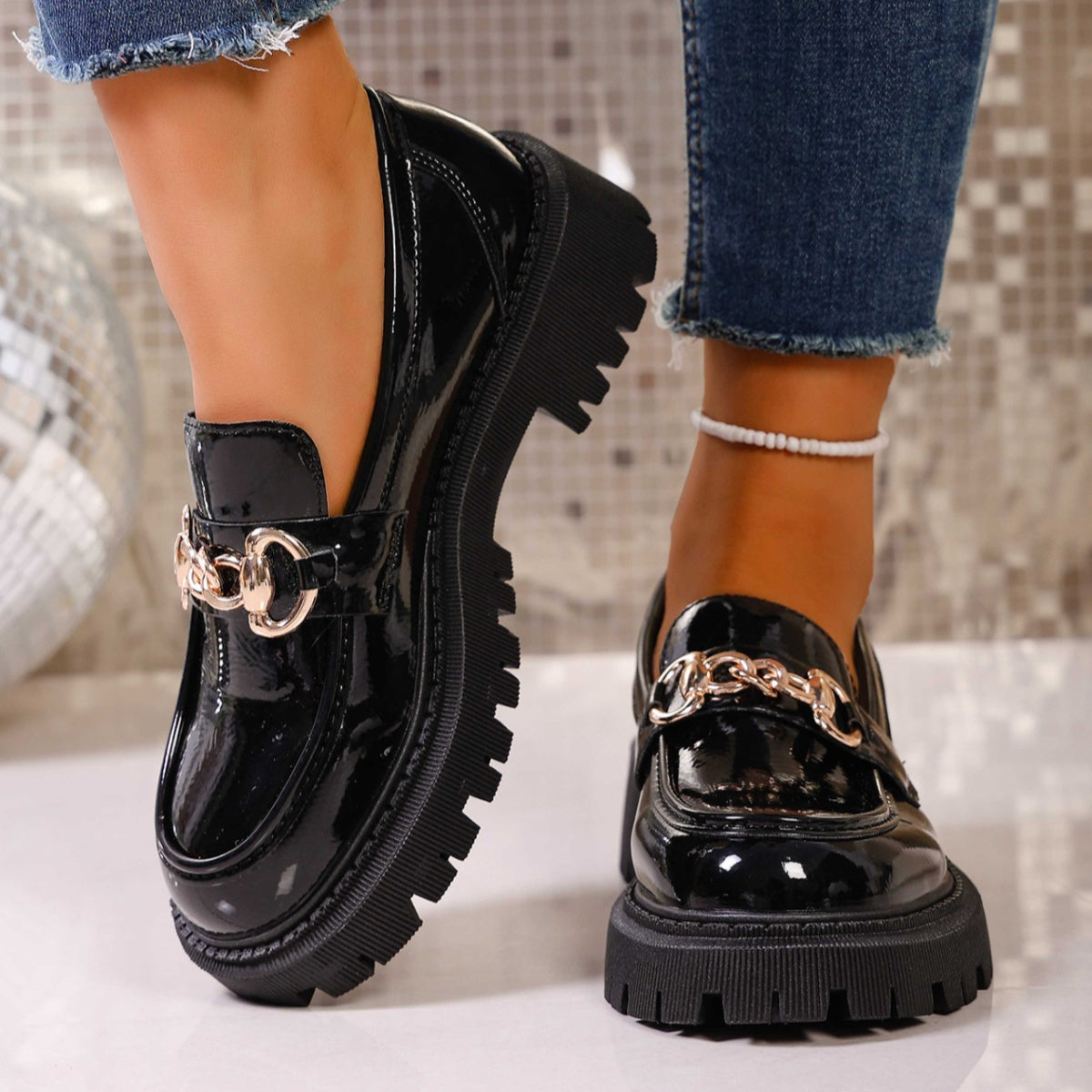 Chunky lug sole loafers in gloss black with gold chain detail.