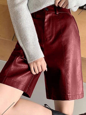 Burgundy vegan leather bermuda shorts with button closure and tailored fit.