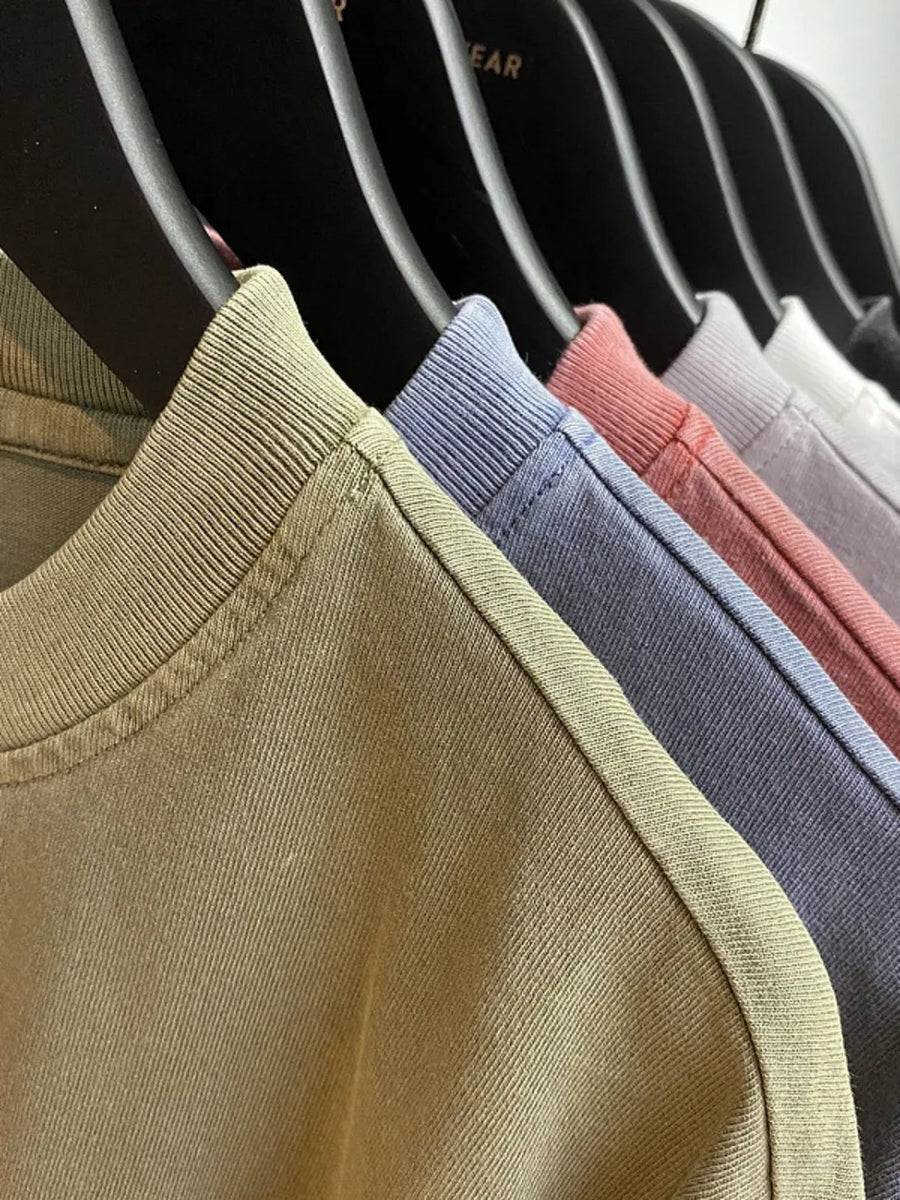 Oversized washed cotton tee in Gum Leaf, Dusty Blue, and Sherbet, showing relaxed fit neckline detail.