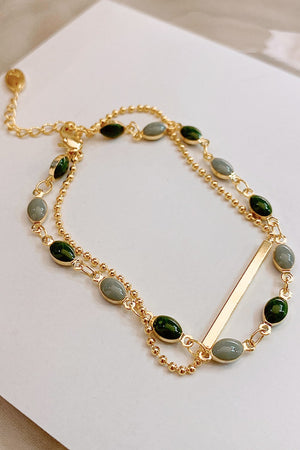 Gold dual chain bracelet with green and grey oval stones and a bar accent