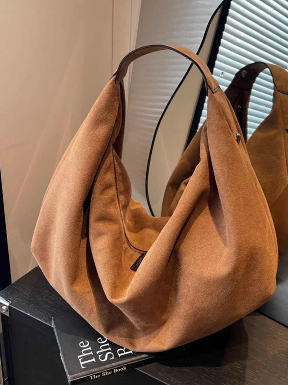 Spacious yellow brown suede shoulder bag with zipper pocket and single strap.
