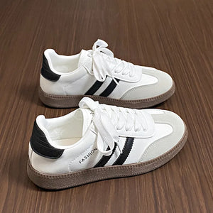 White leather sneakers with black stripes and branding, featuring a casual court-inspired design.