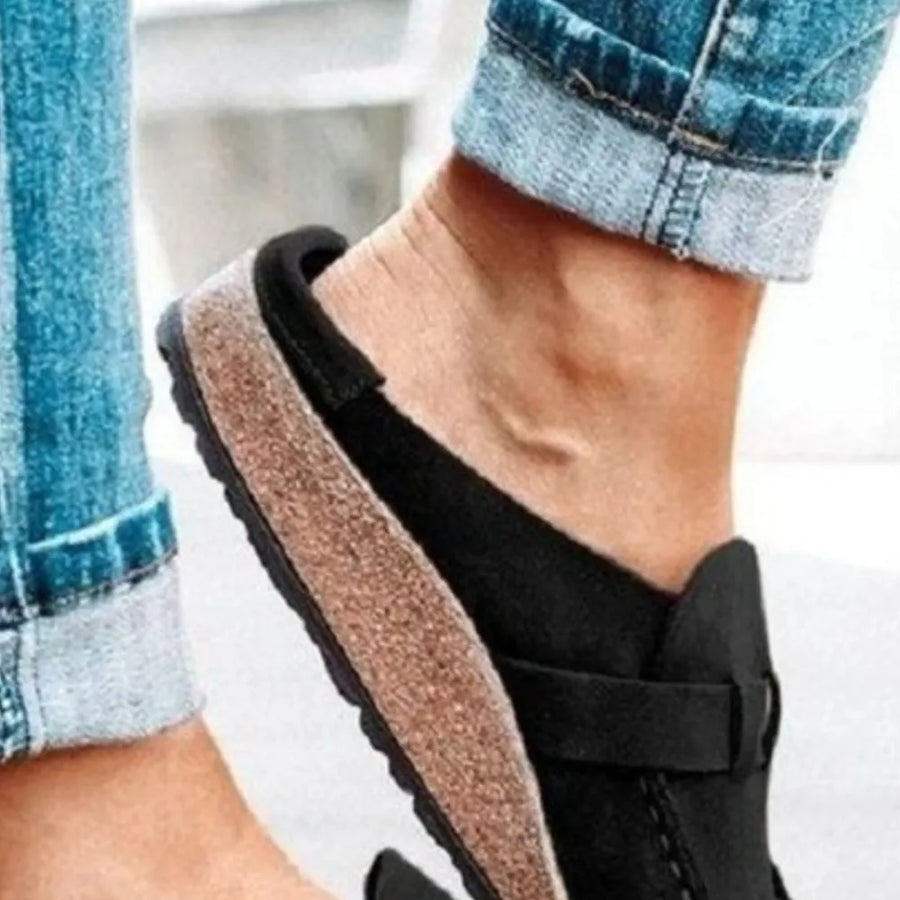 Black suede buckle mule loafers with cork sole detail.