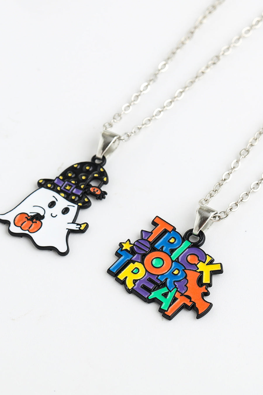 Spooky Season enamel pendant necklaces featuring a ghost with a pumpkin and a trick or treat design.