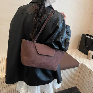 Suede flap tote bag in brown with a single strap and clean design.