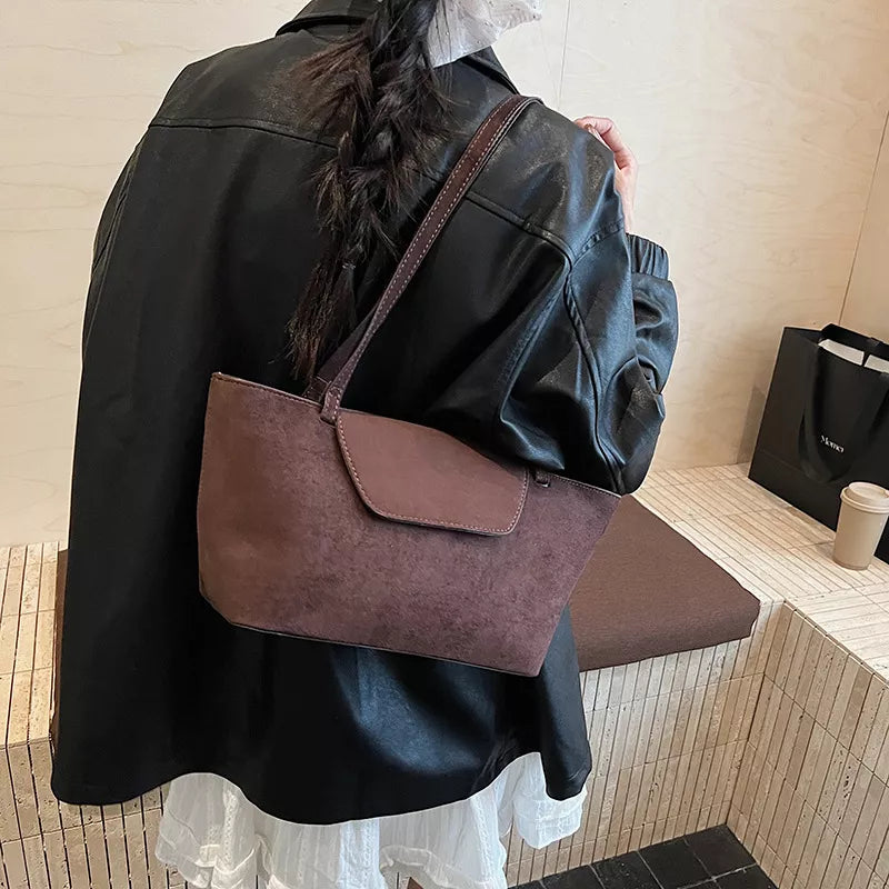 Suede flap tote bag in brown with a single strap and clean design.