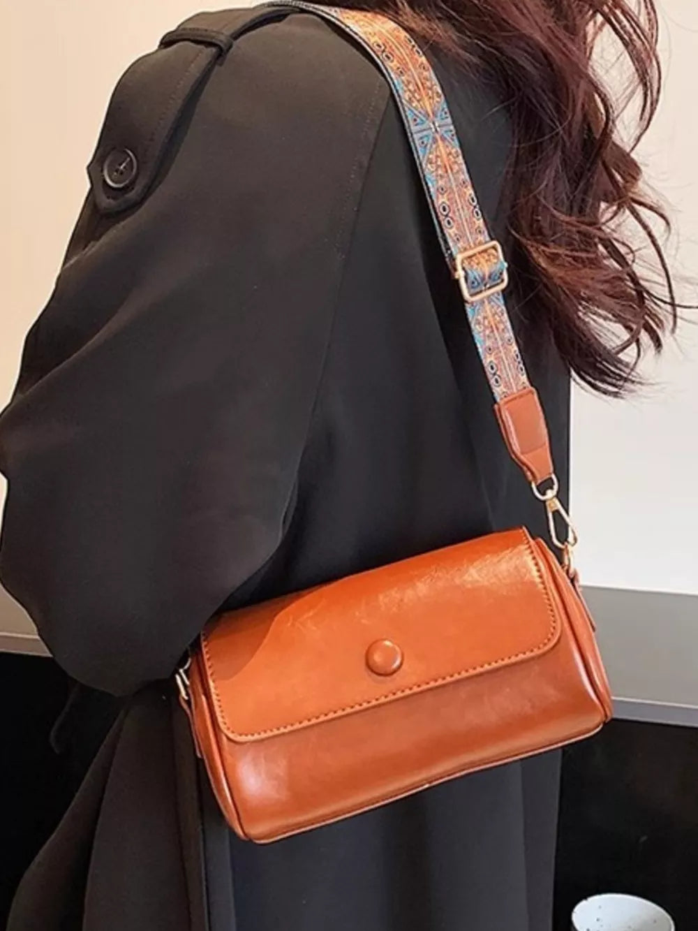 Brown leather crossbody bag with ethnic strap and button closure