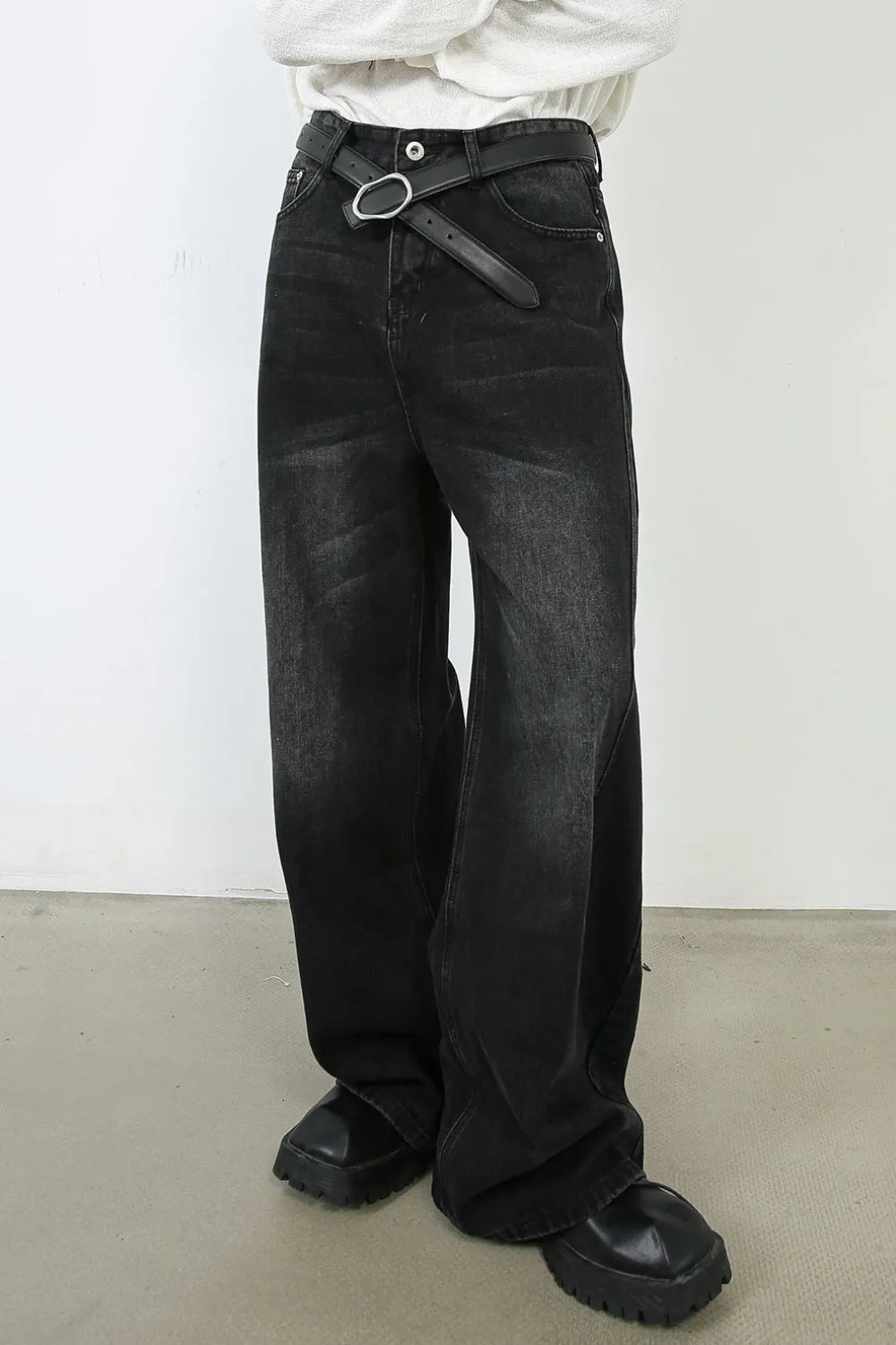 Oversized black wash denim jeans with a wide leg and a statement belt.
