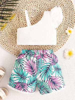 White asymmetrical top with ruffled sleeve and floral print shorts with pom-pom trim
