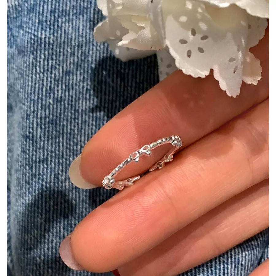 Delicate sterling silver ring with a dainty bow pattern.