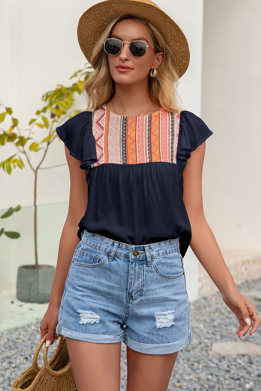 Navy blouse with embroidered yoke and ruffle sleeves, paired with denim shorts.