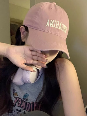 Pink cotton baseball cap with mirrored embroidered lettering and curved brim.