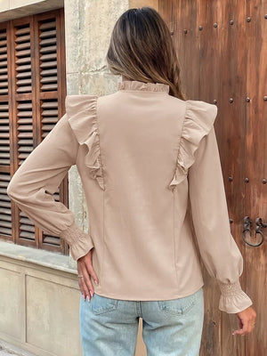 Chic beige long sleeve shirt with ruffled shoulders and cuffs, mock neck, and smocked wrists.