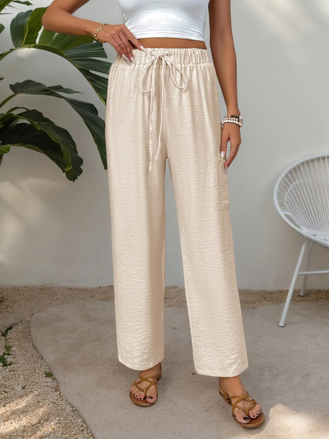 Chic tan waist-tie flare trousers with a textured fabric and side pocket.