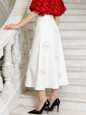 White midi skirt with floral applique, paired with a red rose top and black heels.