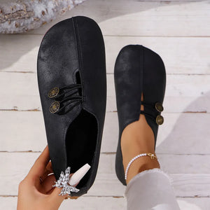 Black leather slip-on flats with antique gold button detail and elastic gore.