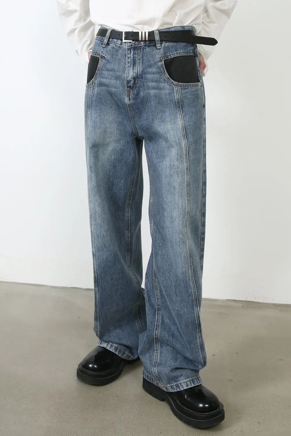 Panel seam denim jeans in medium wash with black pocket details and a relaxed fit.