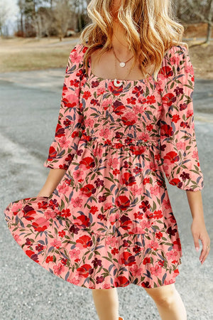Floral smocked mini dress with square neckline and tiered ruffle skirt in pink with red and purple flowers.