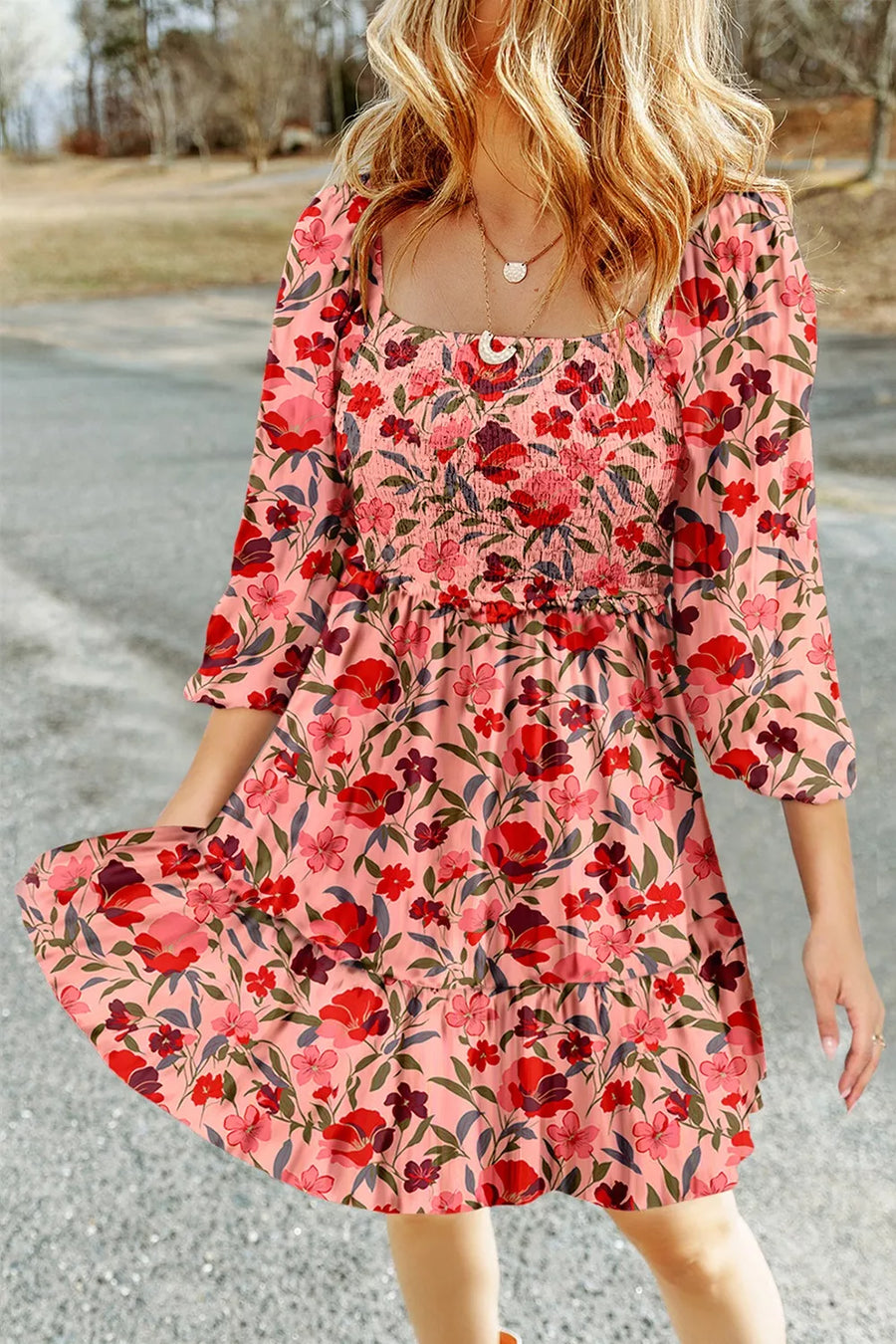 Floral smocked mini dress with square neckline and tiered ruffle skirt in pink with red and purple flowers.