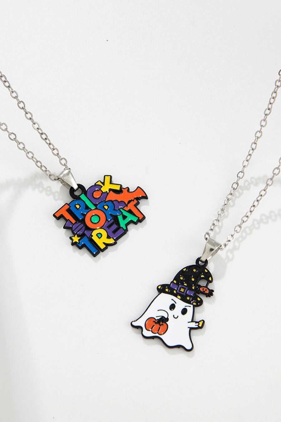 Spooky season enamel pendant necklaces featuring a trick or treat design and a ghost with a pumpkin.