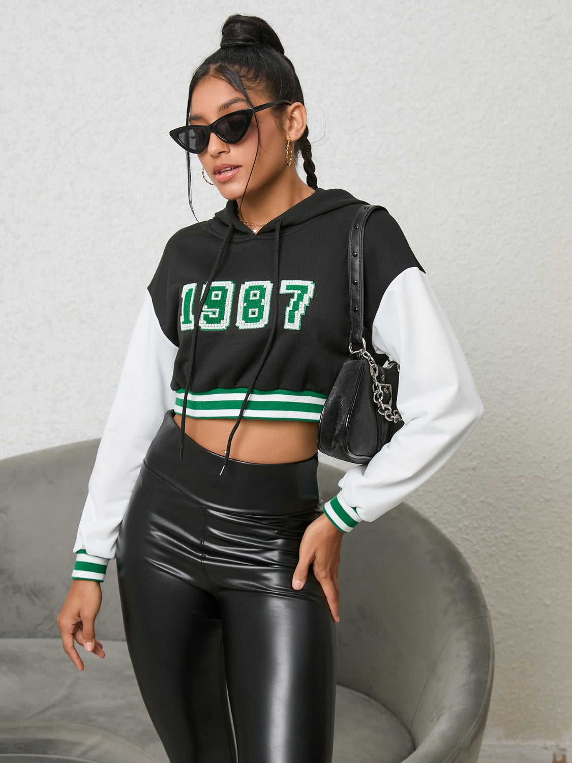 Black cropped hoodie with white sleeves, '87 graphic, and green striped trim.