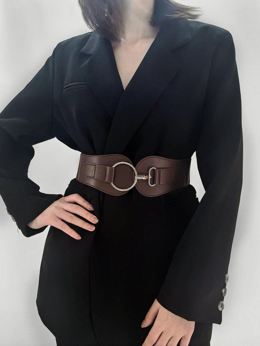 Brown cincher belt with silver buckle detail, worn over a black blazer.