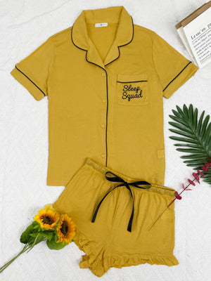 Yellow pajama set with black trim, short sleeves, and ruffled shorts.