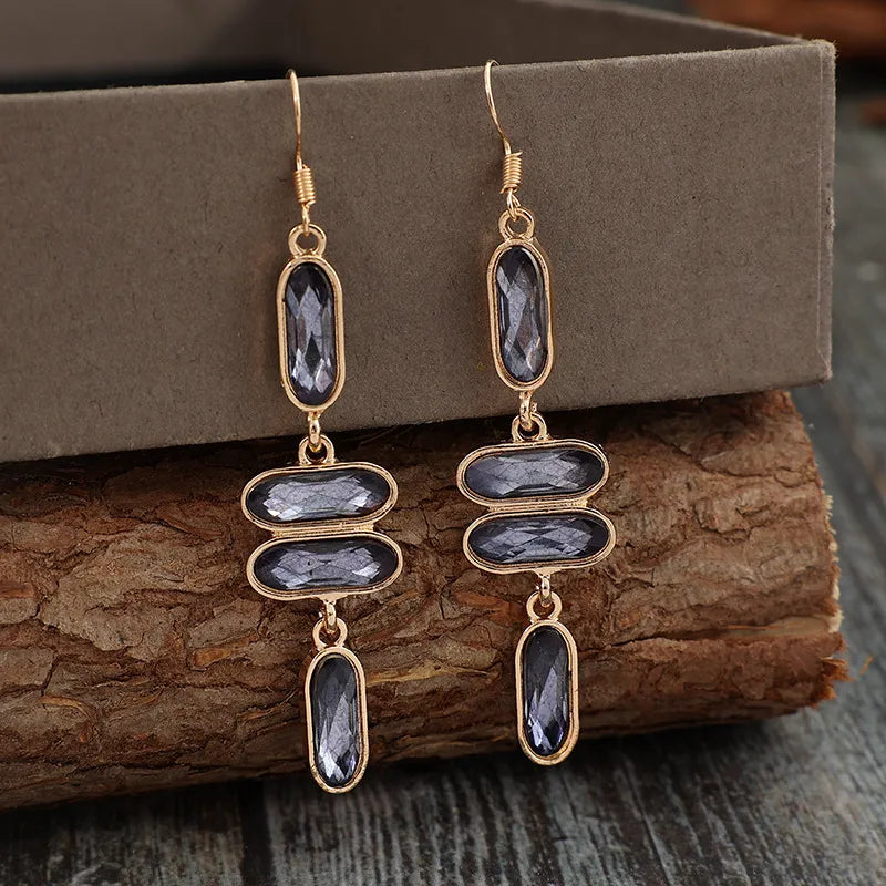 Geometric stone cascade earrings in gold with dark grey faceted stones.