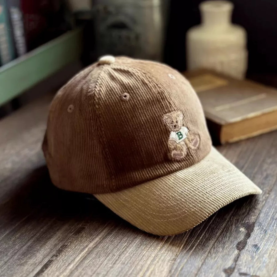 Brown corduroy baseball cap with embroidered teddy bear detail and contrasting tan brim.