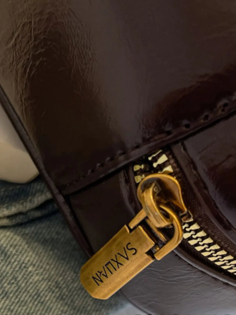 Burgundy patent leather shoulder bag with gold zipper detail.