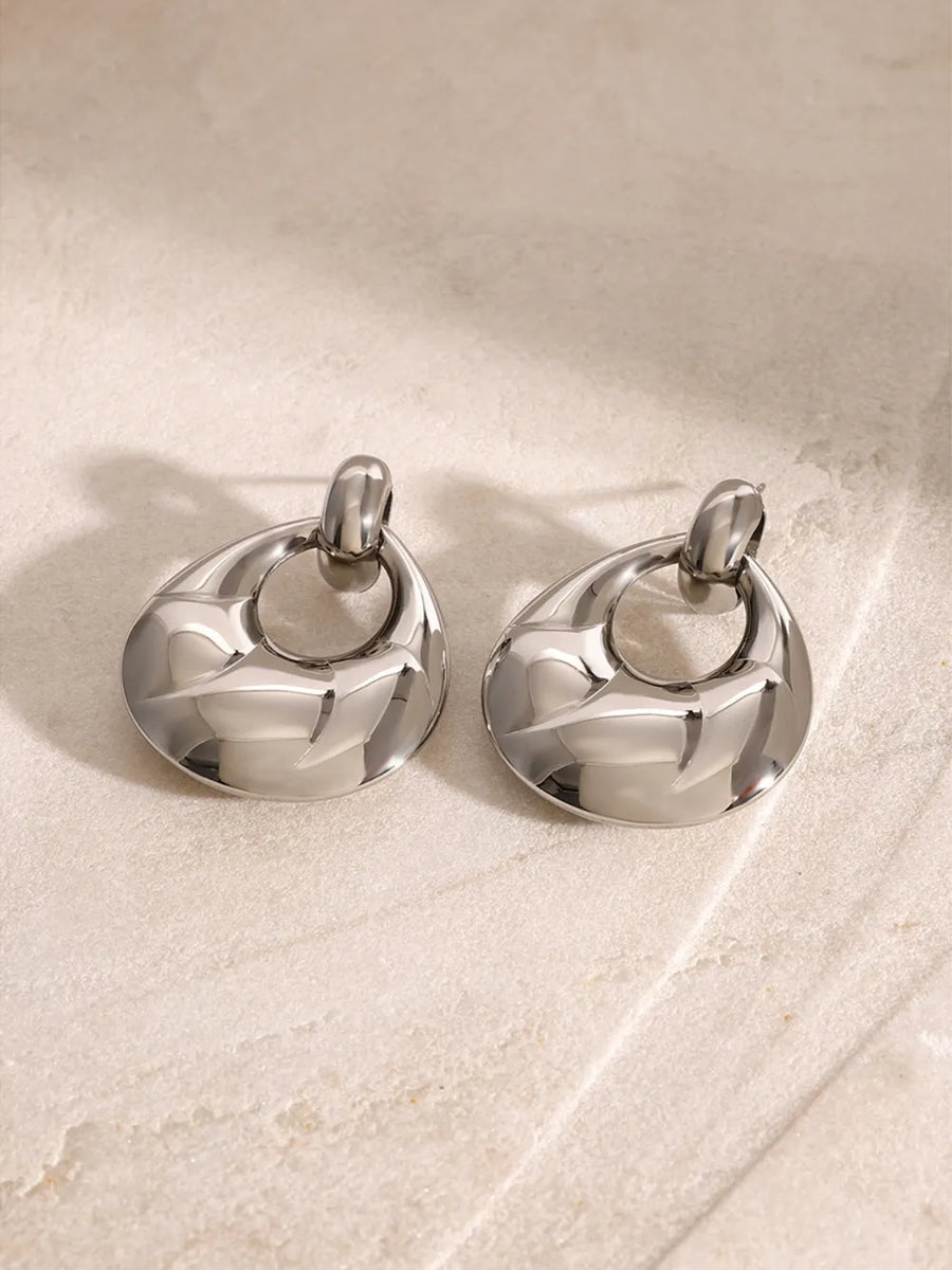Sculpted silver statement earrings with textured detail and a chic, modern design.