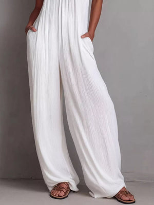 White wide-leg jumpsuit with textured fabric and pockets, styled with sandals.