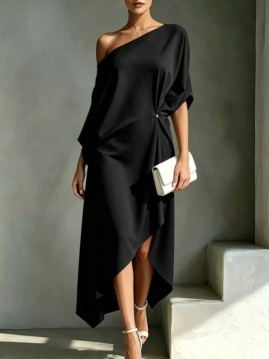 Black one-shoulder midi dress with asymmetric hem and knot detail, styled with white clutch and heels.