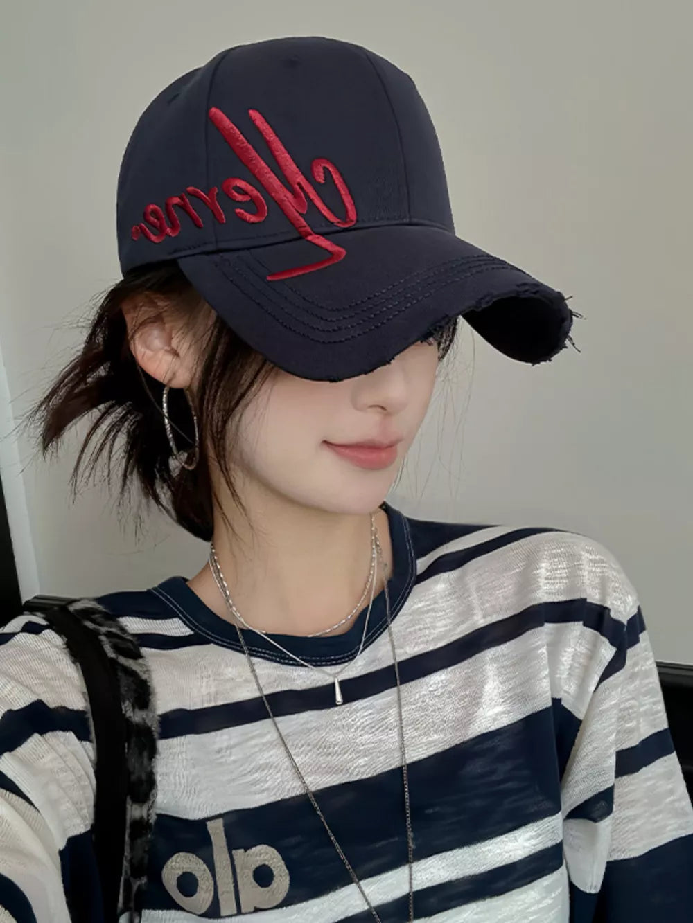 Navy blue distressed baseball cap with red embroidery and frayed brim.