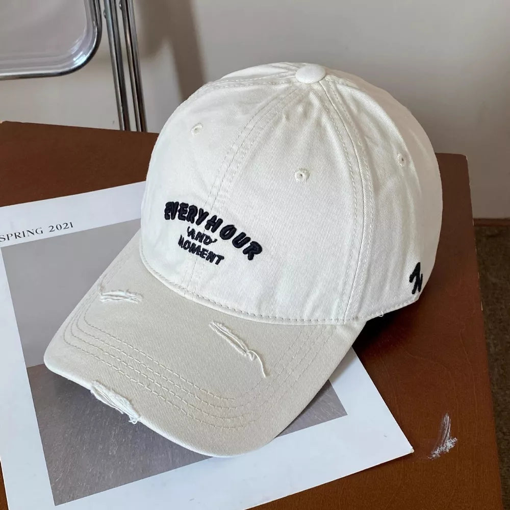 Off-white distressed baseball cap with black embroidery and distressed brim