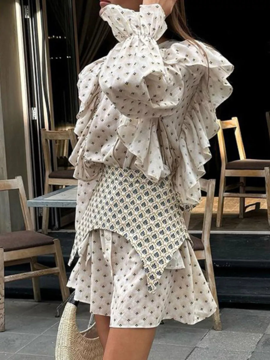 Cream printed dress with ruffled sleeves and a patterned overlay skirt.
