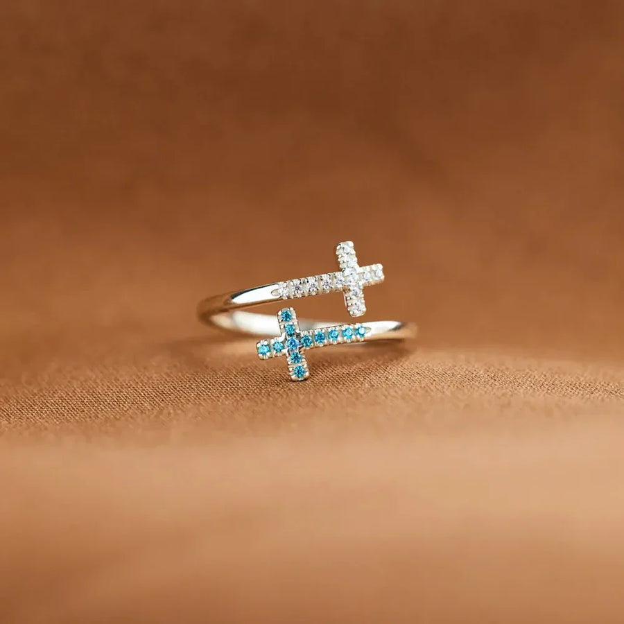 Sterling silver ring with two intertwined crosses, one with clear stones, one with blue stones.